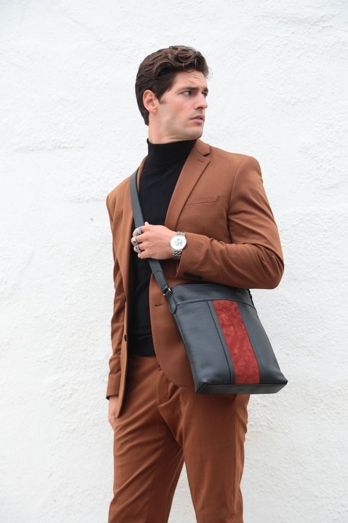 Luis Steven black pebble leather tablet crossbody bag with a red suede stripe worn by a man in a brown suit