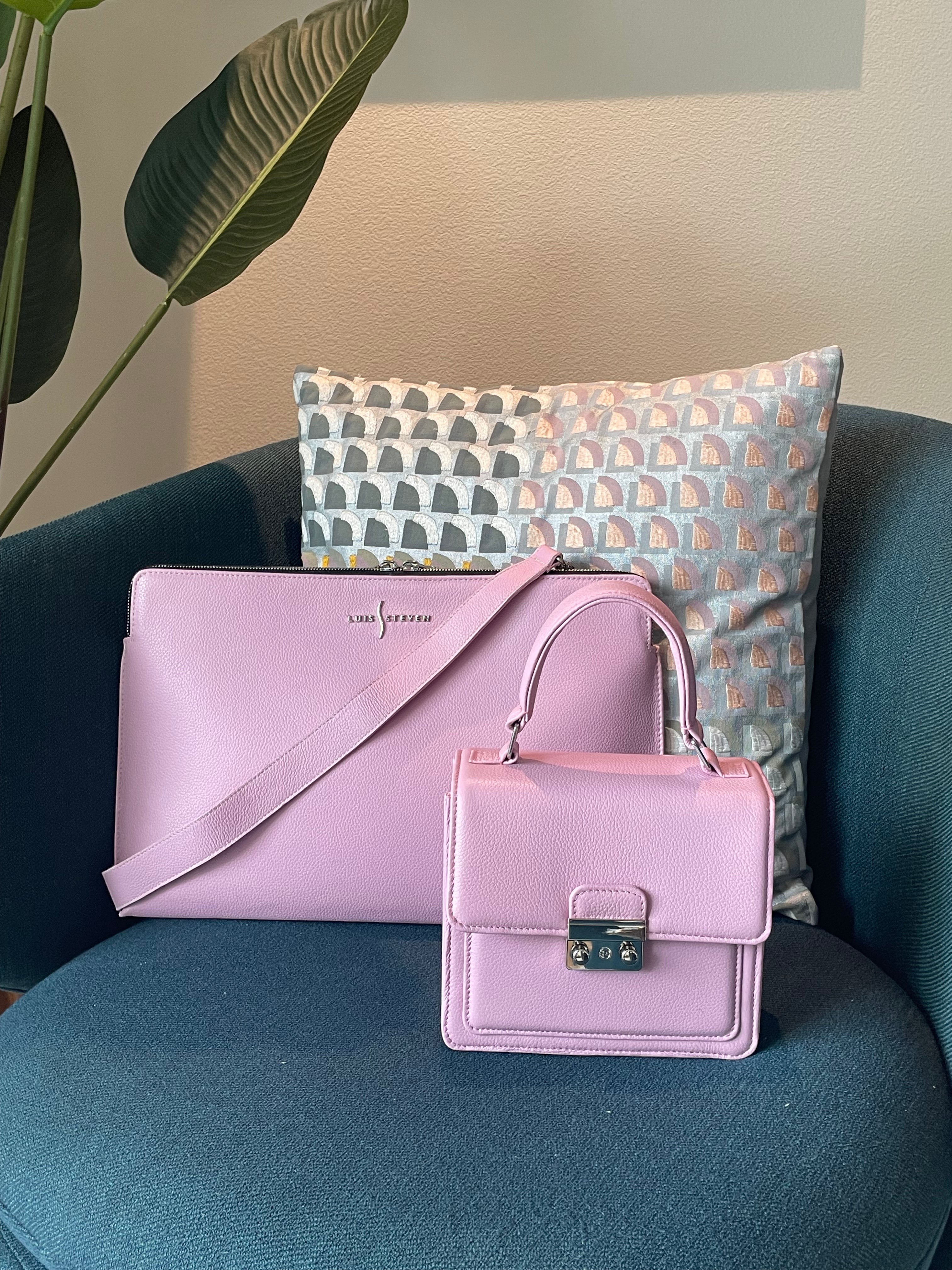 Luis Steven pink pebble leather laptop sleeve and matching handbag on a dark blue chair with a decorative pillow.